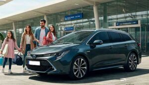 Happy family picking up a black Toyota Corolla Hybrid Touring Sport rental car at Malaga Airport