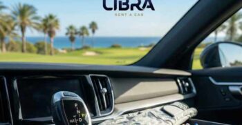 Interior view of a modern rental car showing an automatic gear selector console, a white golf glove, and tees, with a blurred golf course and ocean view in the background and the Libra Rent a Car logo.